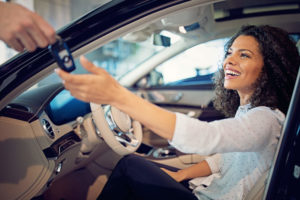 Foto de uma mulher dentro do carro recebendo a chave. IMagem para ilustrar o texto sobre como fazer um bom negócio ao comprar um carro