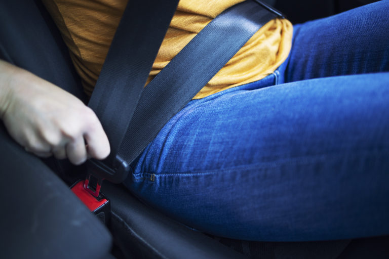 Close up view of driver putting seat belt on.