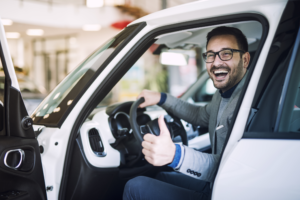 homem branco de terno feliz dentro do carro novo