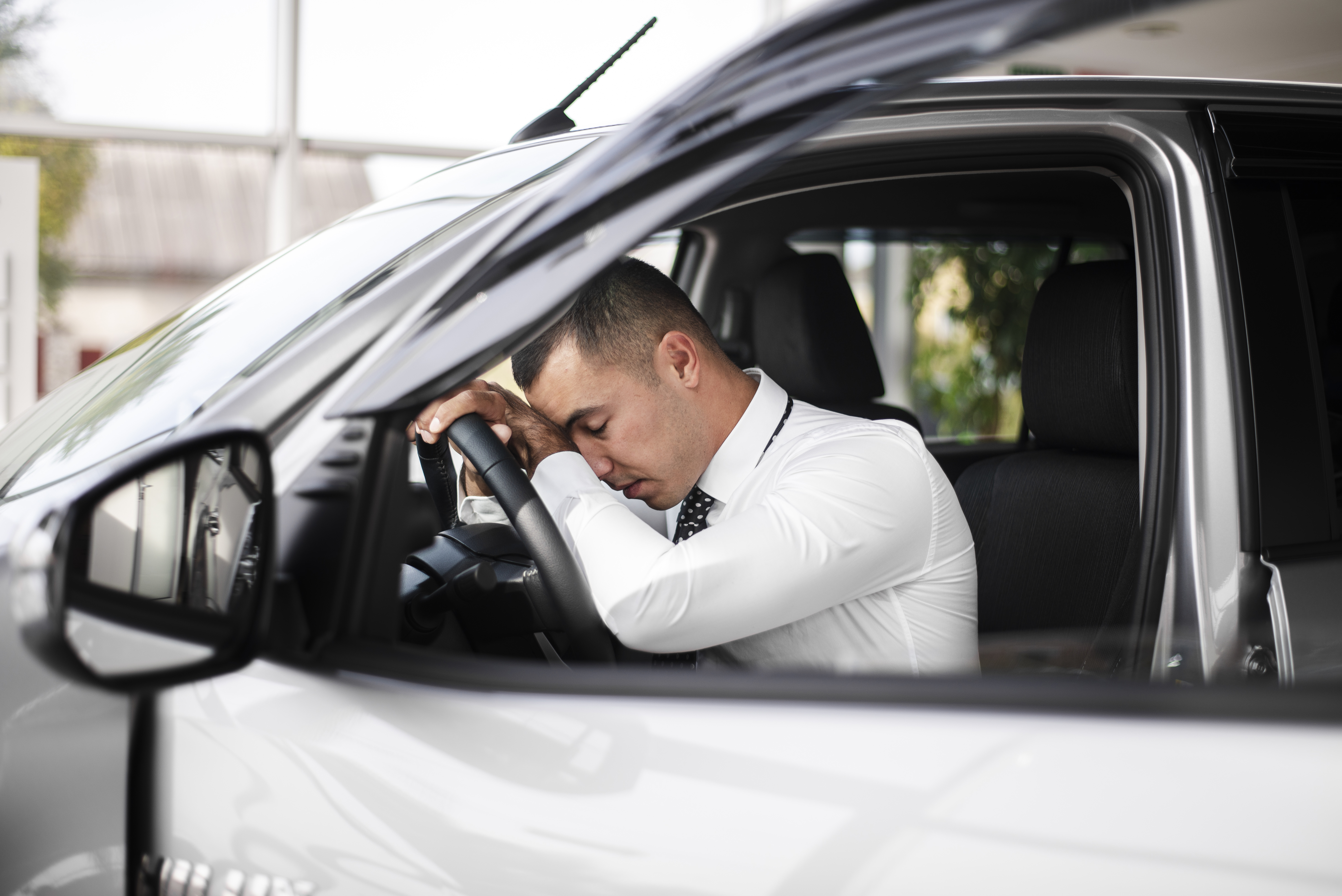 Na imagem, um homem chateado com uma multa de trânsito, ao volante do carro