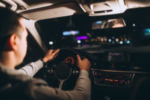 Na imagem, um homem dirige seu carro à noite