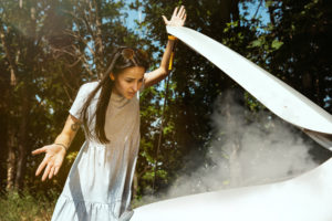 Na imagem, uma mulher enfrenta um problema com seu carro que solta fumaça