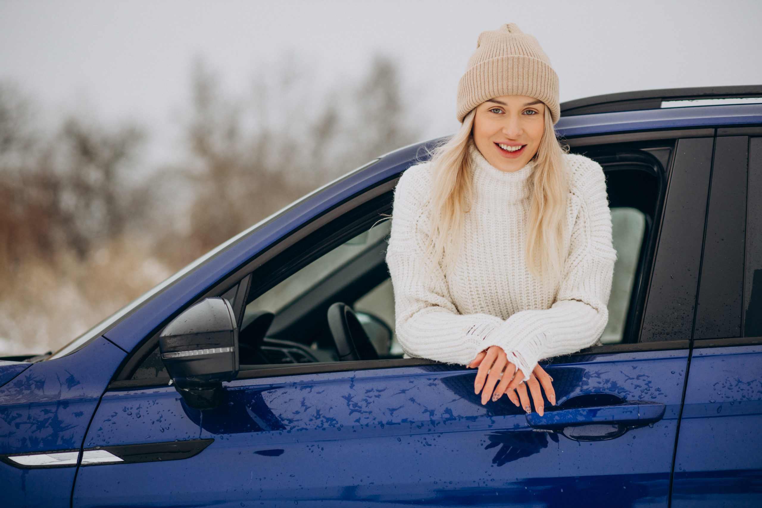 Woman sitting in her new car in a winter park