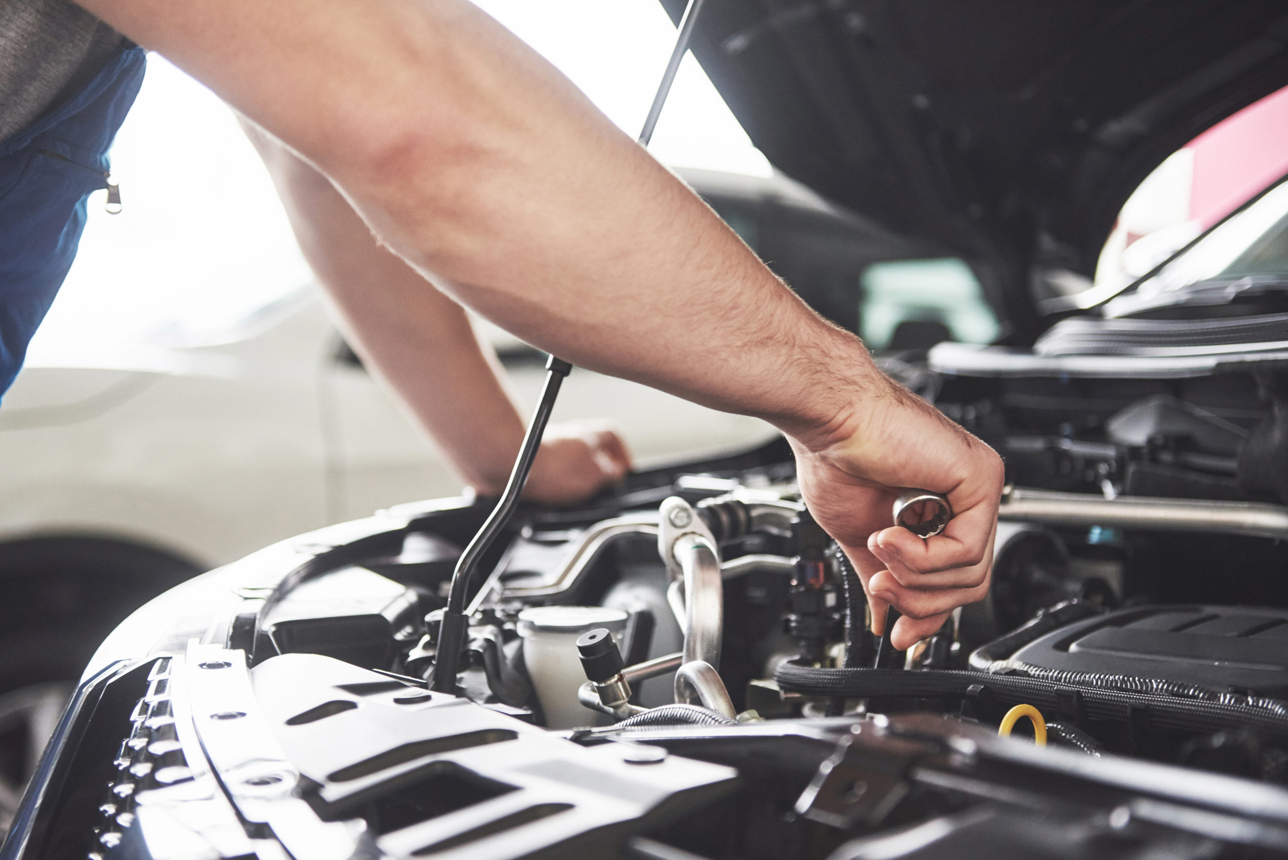 Mãos de um mecânico branco manuseando partes do carro