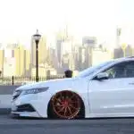 Carro branco rebaixado em cenário urbano, durante o dia
