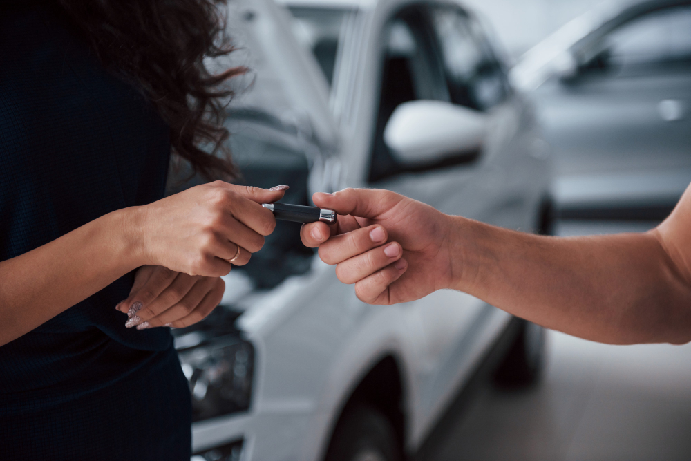 Close das mãos de pessoas brancas, uma passando a chave de um carro para a outra