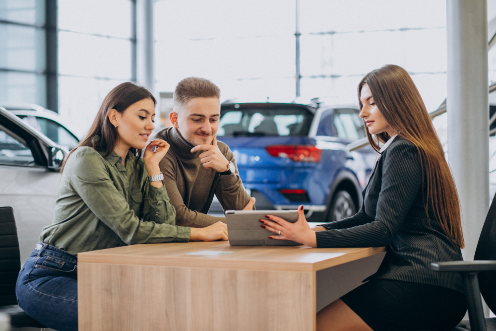 Homem e mulher brancos em uma mesa de negociação financiando um carro com a vendedora