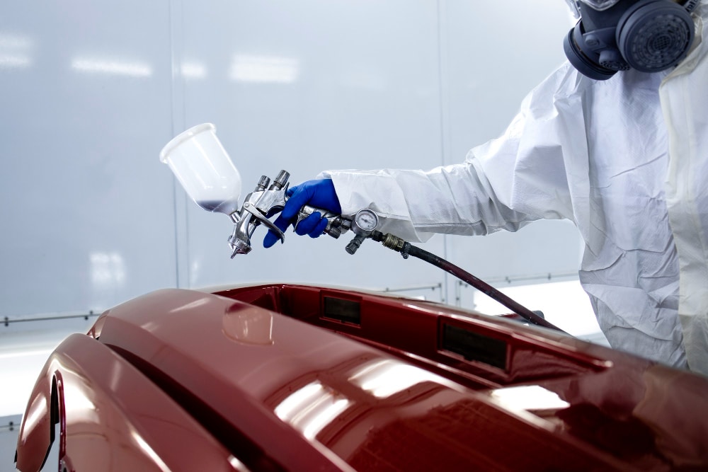 Pessoa usando um jato de tinta para pintar um carro de vermelho