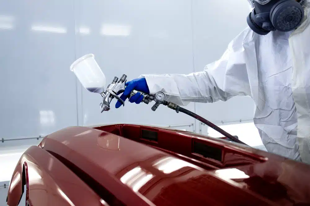 Pessoa usando um jato de tinta para pintar um carro de vermelho