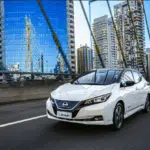 Carro modelo Nissan Leaf brancp andando na cidade