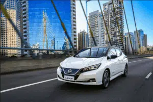 Carro modelo Nissan Leaf brancp andando na cidade