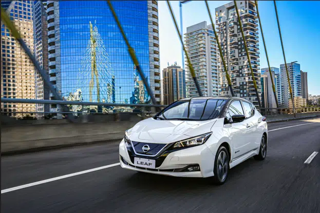 Carro modelo Nissan Leaf brancp andando na cidade
